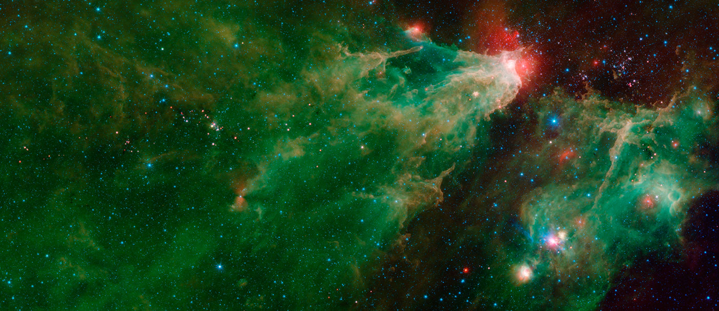 Two cloudy nebula appear in this image, each in shades of green, yellow and red. One appears to blast across the image from the lower left just about to the top of the image just the right of center. At the top end the nebua had a bright white spot with a red halo, and trailing behind to the lower left of the image is a semi-transparent green cloud looking like a dress trailing behind. Taking up the lower right portion of the image is a compact green bundle of clouds, with just a thin strip of black sky between the two nebulae.