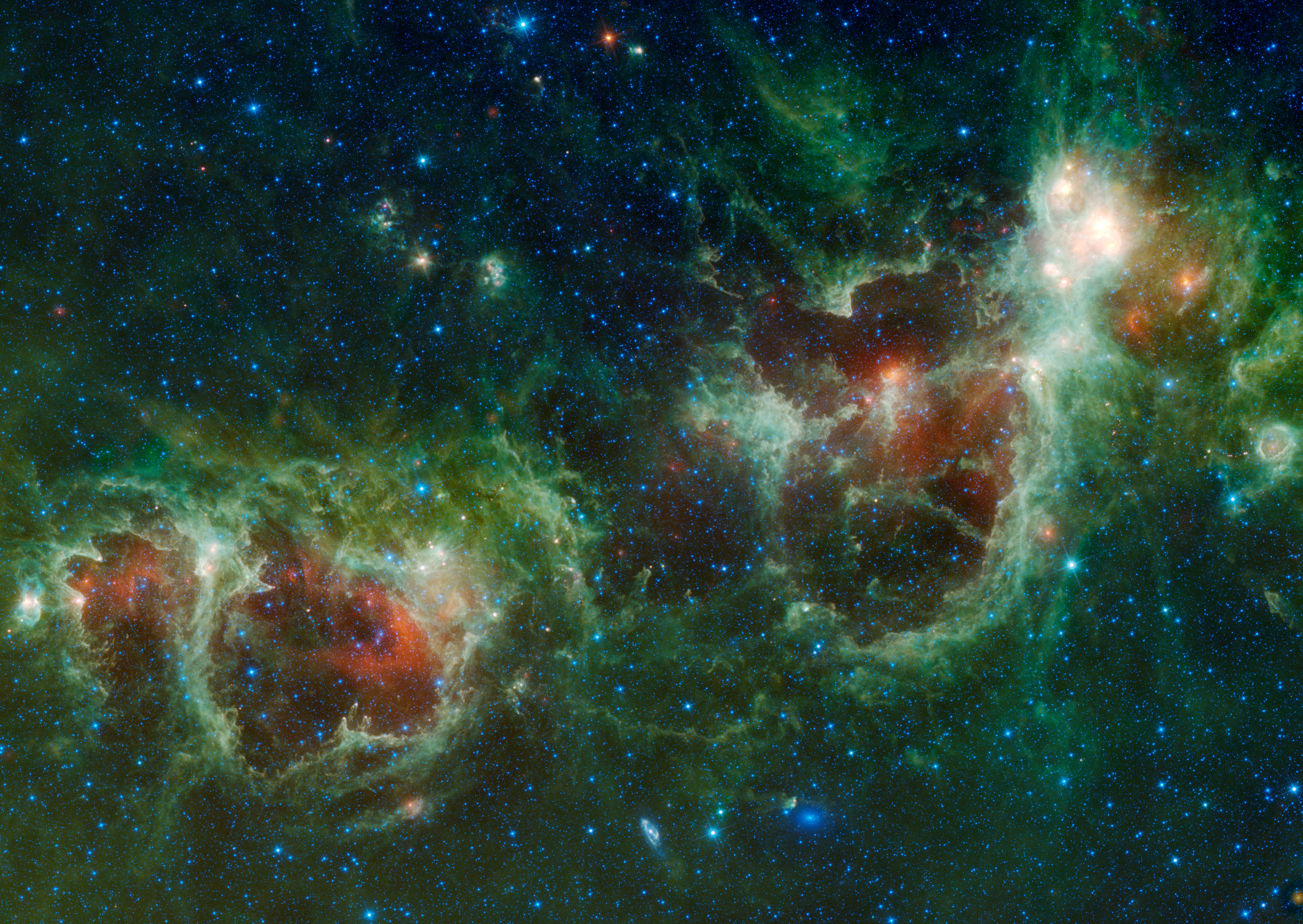 A starry background is covered by green clouds of material. There are two reddish bubbles, each surrounded by a thin tendril of pale green light, one lies at the lower left of the image, the other in the center right.